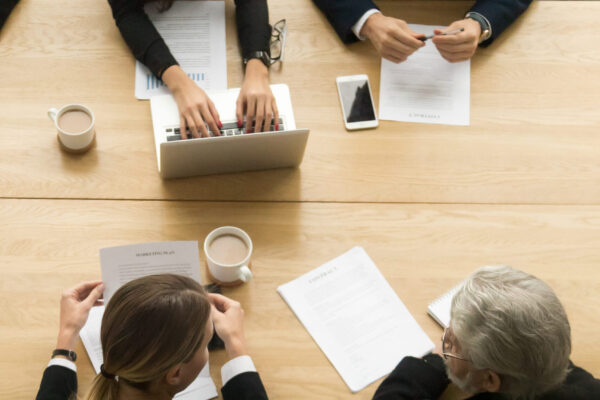 Diverse business colleagues working together at meeting, vertica Diverse business colleagues working together talking planning at meeting table, multiracial young and senior people preparing for contract negotiations talking during teamwork, vertical top view