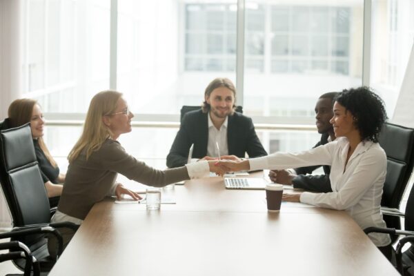 diverse-smiling-businesswomen-shaking-hands-greeting-multiracial-group-meeting diverse-smiling-businesswomen-shaking-hands-greeting-multiracial-group-meeting