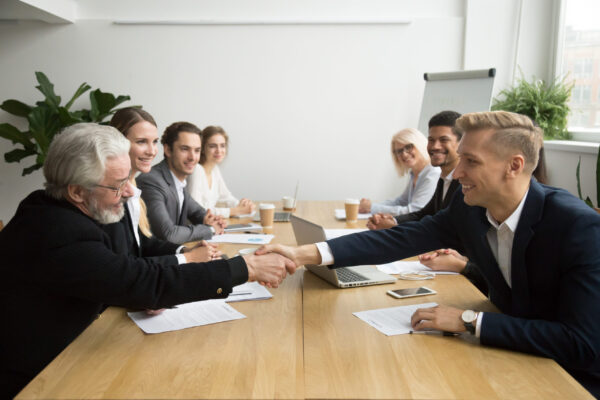 Senior investor buying startup handshaking young entrepreneur at Young and old male partners shaking hands after signing contracts at group multiracial meeting, senior investor buying startup promising support handshaking entrepreneur, partnership deal concept